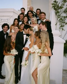 a group of people standing next to each other in front of a white building with flowers