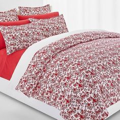 a bed with red and white sheets and pillows