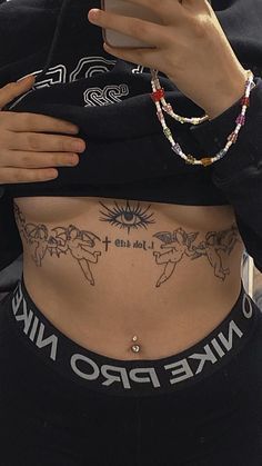 a woman with tattoos on her stomach looking at her cell phone while wearing a black crop top