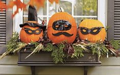 three pumpkins are sitting on a window sill decorated with black and orange masks