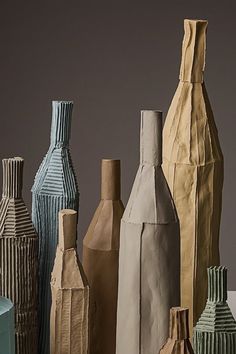 there are many different colored vases on the table together and one is made out of paper