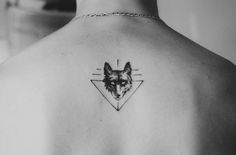 the back of a woman's shoulder with a tattoo of a wolf on it