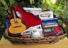 a basket filled with musical instruments sitting on top of a wooden table next to plants