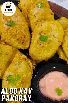 a plate with some food on it and sauce in the bowl next to it that says aloo kay pakoray