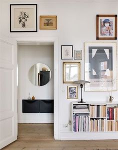 a living room filled with lots of books and pictures on the wall next to a doorway