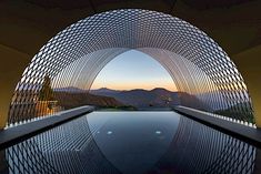 the reflection of mountains is seen through an arch in this photo taken from inside a swimming pool