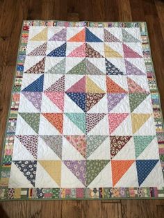 a multicolored quilt is laying on the floor next to a wooden table top