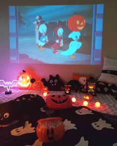 halloween decorations are on the bed in front of a screen with cartoon characters and pumpkins