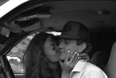 a man and woman kissing in the back seat of a car