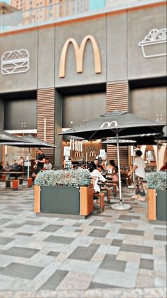 people sitting at tables in front of a mcdonald's restaurant