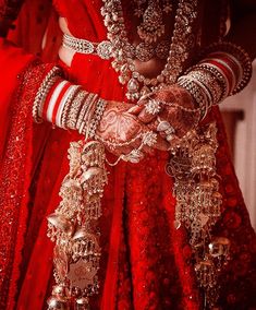 a woman in red and gold outfit with jewelry on her hands