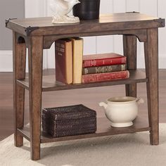 a wooden table with books on it and a vase next to the end table in front of it