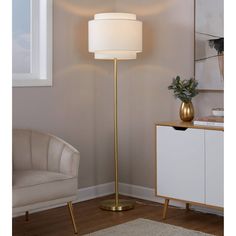 a floor lamp with a white shade on it in a living room next to a chair