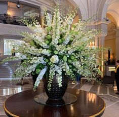 a large vase with white flowers on a table in a hotel lobby or reception room