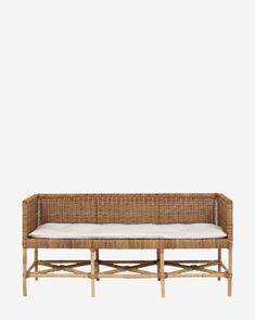 a wicker bench with white cushions on it