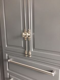 a close up of a door handle on a gray cabinet with silver handles and knobs