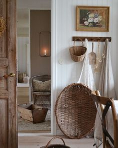 a wicker hanging chair next to a wooden door in a room with white walls