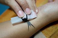 a person with a black and white tattoo on their arm holding onto a piece of paper