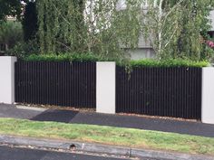 a black and white fence in front of a house with green grass on the side