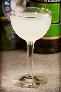 a glass filled with white liquid sitting on top of a counter next to two bottles