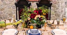 the table is set with plates, silverware and flowers in vases on it