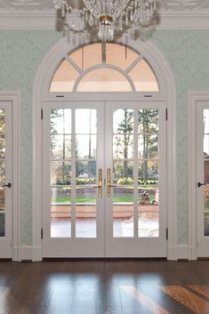 an empty room with french doors and chandelier