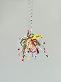 a multicolored beaded ornament hanging from a chain on a gray background