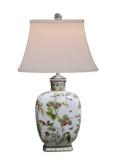 a lamp with a white shade on it and flowers painted on the bottom, sitting next to a light bulb