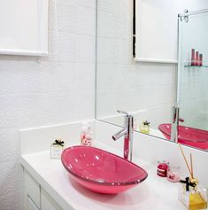 a pink bowl sink sitting on top of a white counter next to a bathroom mirror