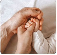 two people holding hands on top of a bed