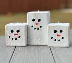 three snowmen made out of blocks sitting on top of a wooden table