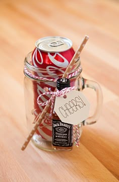 a glass jar filled with red and white soda cans sitting on top of a wooden table