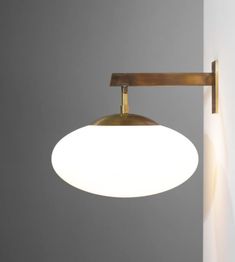 a white light hanging from the side of a wall next to a gray wall with a lamp on it