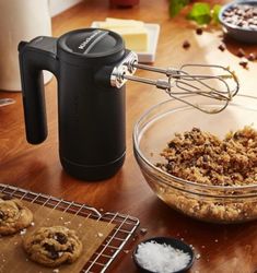 a table topped with cookies and an electric hand mixer next to a bowl filled with cookie crumbs