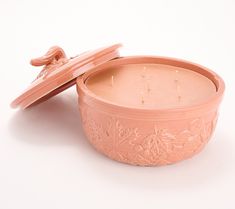 a pink candle in a bowl with a lid