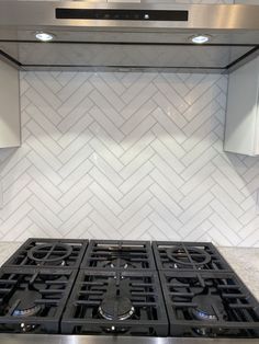 a stove top oven sitting inside of a kitchen next to white cabinets and counter tops