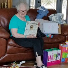 an older woman sitting on a couch reading a book