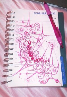 a spiral notebook with pink ink on it and a pen resting on top of it