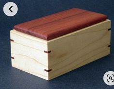 a small wooden box with a red lid