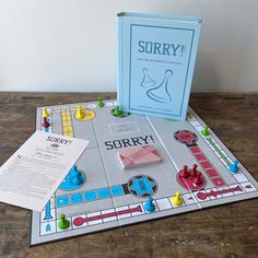 a board game that is sitting on a table next to an open book and some pieces of paper