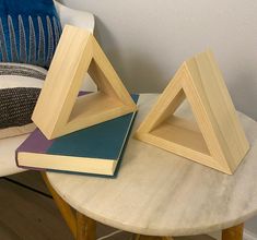 three books are stacked on top of each other near a table with a blue pillow