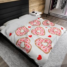 a bed with pink frosted donuts and hearts on it