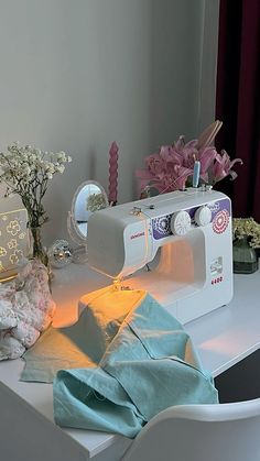 a sewing machine sitting on top of a white table next to flowers and other items