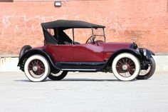 an old car parked in front of a brick building