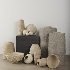 several vases and bowls are stacked on top of each other in front of a white wall