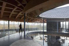 a man is standing in the middle of a room with glass walls and large windows