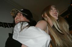 two young women laughing and dancing together at a party