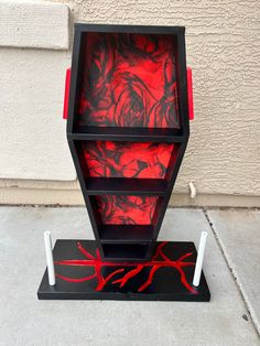 a red and black book shelf sitting on top of a sidewalk