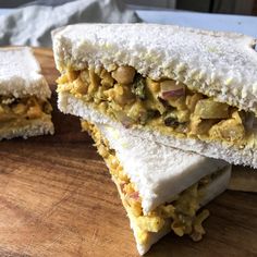 two sandwiches cut in half sitting on top of a wooden cutting board