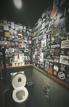 a white toilet sitting inside of a bathroom next to a wall covered in stickers